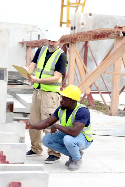 istock Harmony diversity people working together at workplace, senior foreman and African engineer holding document file to inspection at construction site. Workers working together at building site. 2160848479