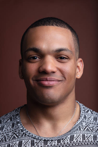 istock Studio portrait of young man smiling and posing on brown backgro 2160852352