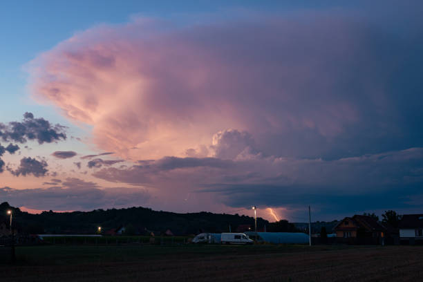 Huge thunderstorm over the Romanian countryside is illuminated in pink by the already setting sun.
