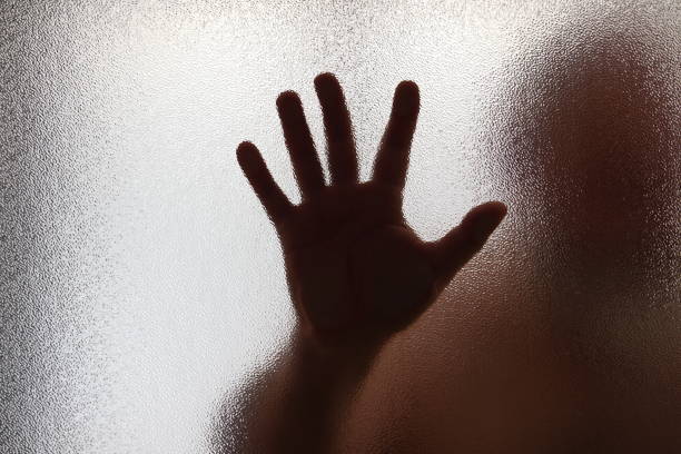 istock Man hand behind the glass 2160855023