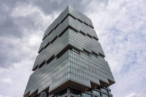 A tall building with a lot of windows and a cloudy sky in the background