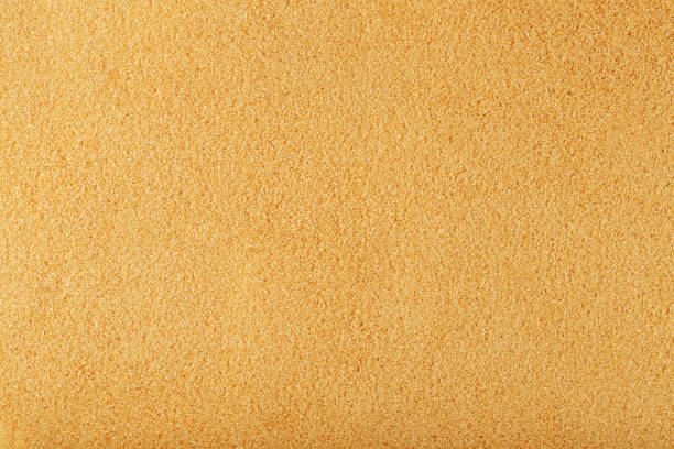 Texture of golden sand on the beach with a solid background in full screen. Free space, top view