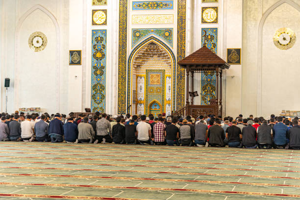 Man performing islamic prayer inside a mosque, kneeling on prayer rug with peaceful and spiritual atmosphere during worship
