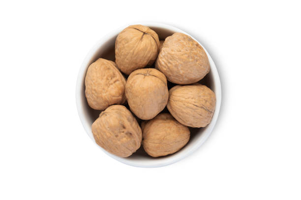 istock Ceramic bowl with organic walnut nuts with shell isolated on white background.Top view. 2160864216