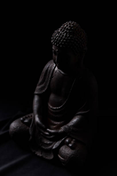 Meditating Buddha Statue on dark background. Soft focus. Close up. Copy space.