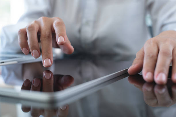 istock Businesswoman using digital tablet, finger touching on screen on office table, close up. Business woman surfing the internet, searching the information on digital tablet and working on laptop computer at office 2160870263