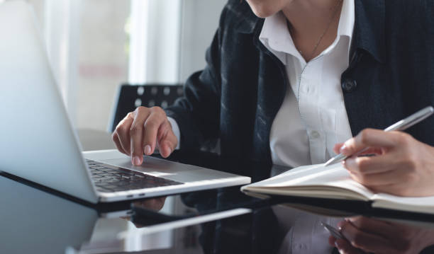 istock Business woman working on laptop computer, planning work project and searching the information at office. Female student online studying and writing on paper notebook, e-learning, online study concept 2160873809