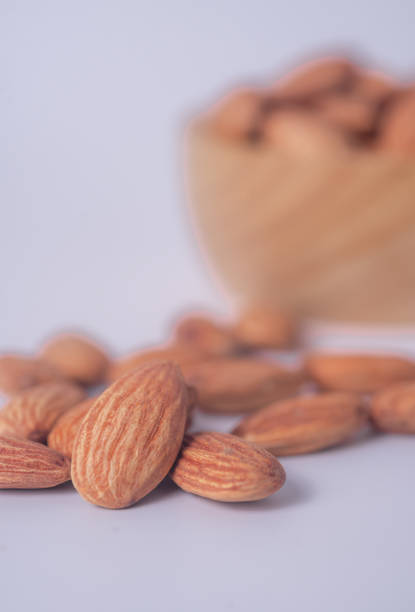 Almond snack fruit in wooden bowl on blurred white background