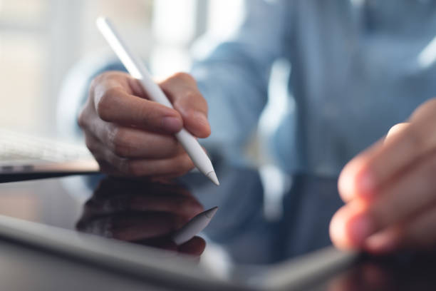 istock Business woman using stylus pen signing e-document on digital tablet via mobile app at office, proofing document, e-signing. Graphic designer working on graphic tablet, close up 2160876660