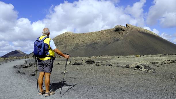 istock Active senior on the lava rock path contemplating the volcano in front 2160880852