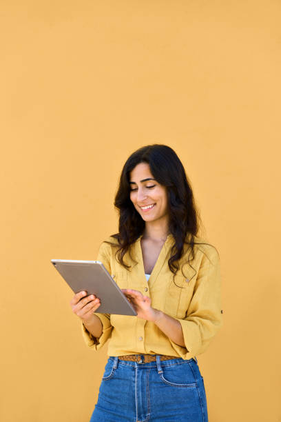 istock Vertical portrait young woman holding digital pad computer isolated. Middle eastern brunette female student girl working online using web tablet application app for elearning, studying, communicating 2160892537