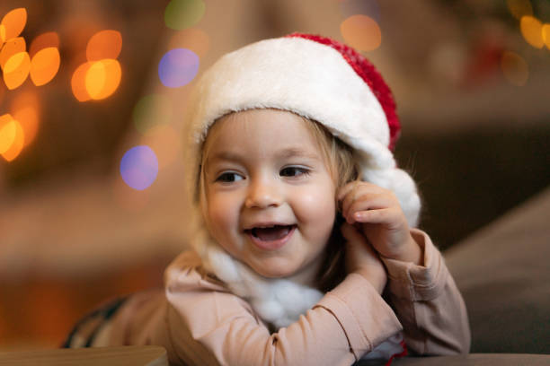 Close-up portrait of joyful little girl whit Santa hat at home