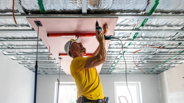 istock The worker screwing plasterboard to the ceiling. He is using special electric screwdriver. A red plasterboard improve the fire resistance of ceiling structures. 2160903868