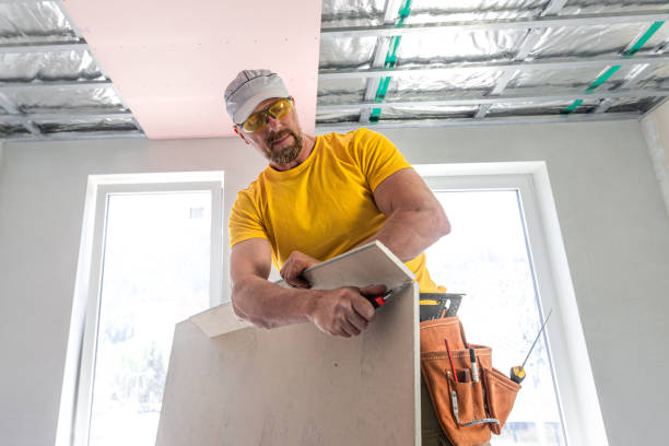 istock The worker make a plasterboard ceiling. He doing adjusts a size of the board using knife cutter. A red plasterboard improve the fire resistance of ceiling structures. 2160903878