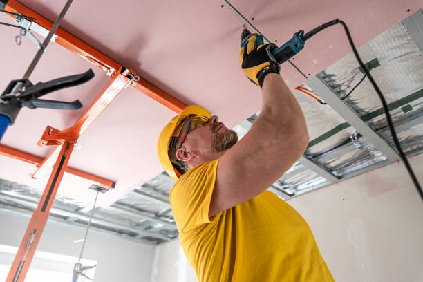 istock The worker screwing plasterboard to the ceiling. He is using special electric screwdriver. A red plasterboard improve the fire resistance of ceiling structures. 2160903889