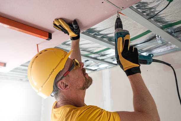 istock The worker screwing plasterboard to the ceiling. He is using special electric screwdriver. A red plasterboard improve the fire resistance of ceiling structures. 2160903893