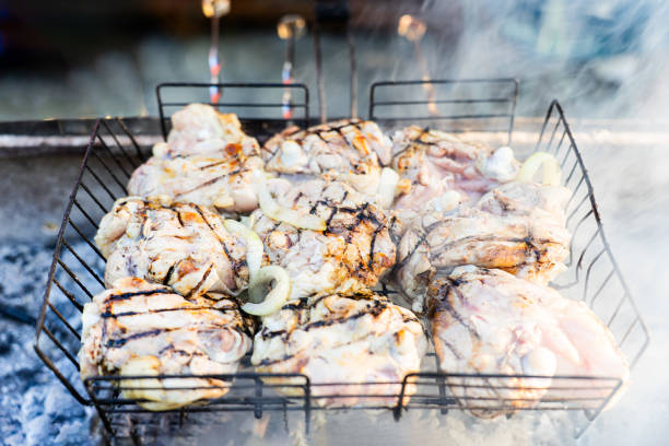 Chicken skewers being grilled on a charcoal barbecue, with smoke rising.