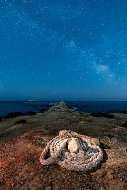 Wide-angle landscape photography at night, in which we can see a mooring rope of a boat and the Milky Way in the background, on the island of Tabarca, province of Alicante, Spain