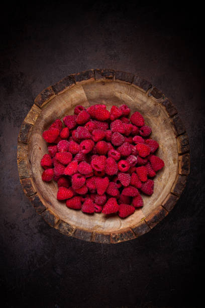 fresh raspberries in a wooden bowl, food background, concept, food styling, on a dark table, top view, no people