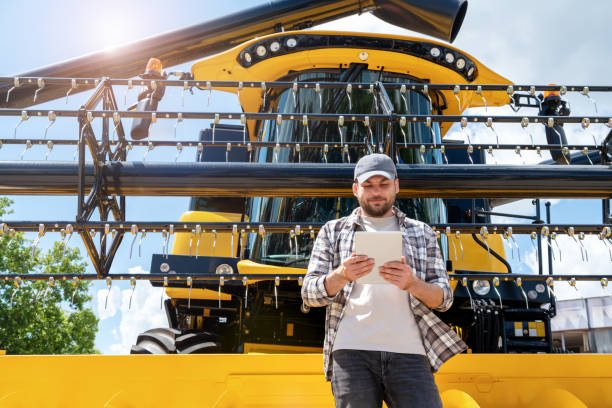 istock An agricultural worker uses a digital tablet while standing in front of a new combine harvester. Leasing agreement, dealership of agricultural machinery. 2160907497