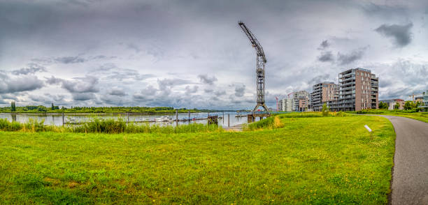 Temse, Belgium - A green grassy park with a tall crane overlooking a river, and an apartment building in the background.
