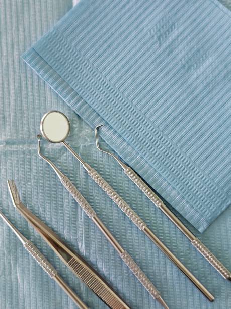 A set of sterile dental tools lie on a blue paper patient bib
