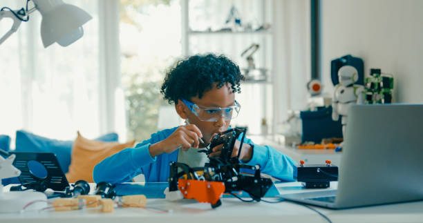 istock Young African-American boy in STEM education by assembling robot at home. STEM Education robotics courses online. 2160910146