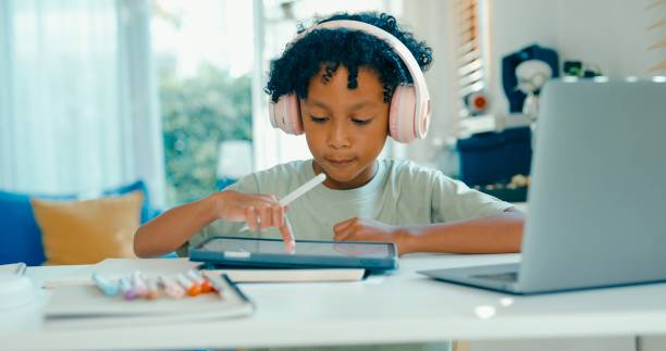 istock Young African-American boy uses digital tablet and stylus for schoolwork while participating in e-learning session at home. Education courses online. 2160910210