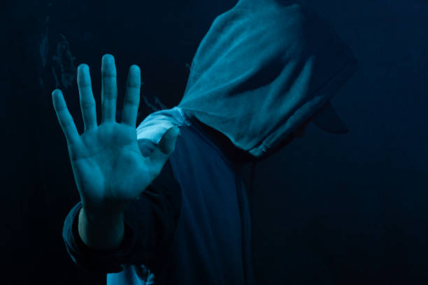 istock Mysterious young man in a sweatshirt showing his palm to the camera. Face hidden. Studio portrait. 2160925007