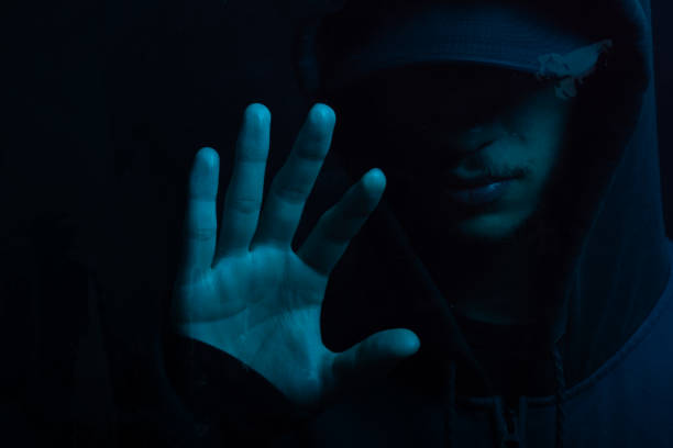 istock Mysterious young man in a sweatshirt showing his palm to the camera. Face hidden. Studio portrait. 2160925010