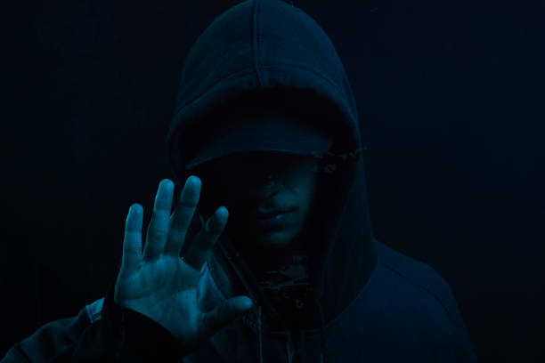 istock Mysterious young man in a sweatshirt showing his palm to the camera. Face hidden. Studio portrait. 2160925017