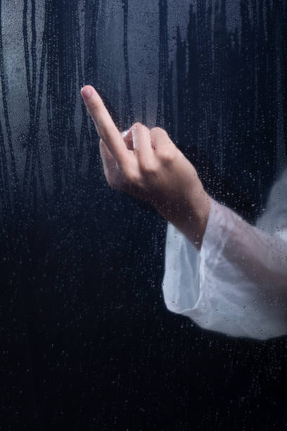 istock A man hand gesturing to the camera behind wet glass. Studio portrait. 2160925043