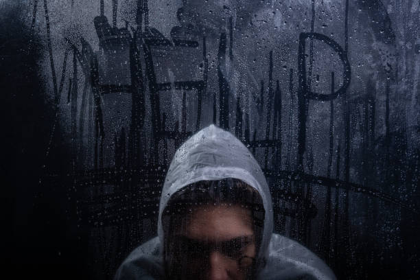 The word help written on a transparent glass wet with water drops. Studio shot. Dark background.
