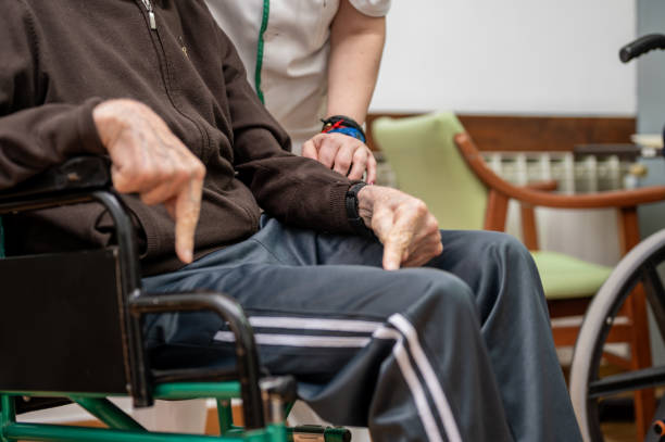 istock Caregiver assisting elderly man in dining room at nursing home. 2160928728