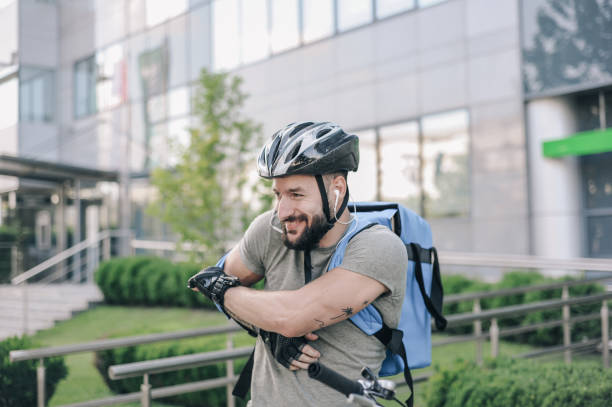 Man in cycling gear standing in front of modern building, ready for a ride on a sunny day.