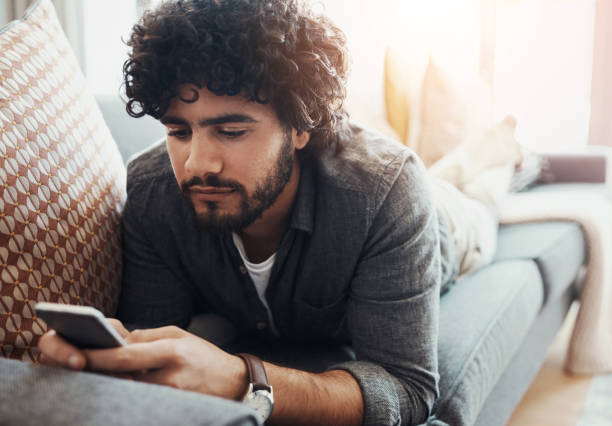 istock Home, relax and man with phone on sofa for social network, communication and digital connection. Calm, and male person with tech in living room for sports news, information and reading online results 2160933856