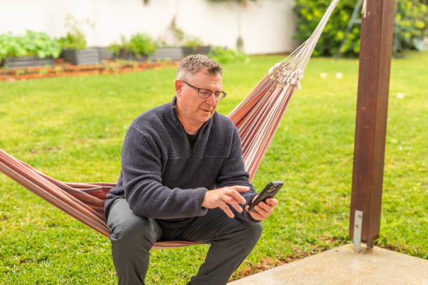 istock Middle aged using a mobile phone with a credit card in his backyard 2160935618