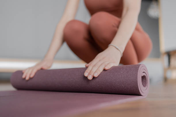 istock Woman trainer rolling out a mat after class. Rolled yoga mats in a studio create a peaceful atmosphere for meditation and exercise. 2160937997