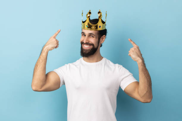 Satisfied happy man pointing fingers on golden crown on his head, showing his authority,