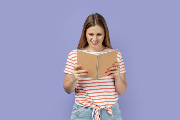 istock Woman holding and reading book, being very interested in plot, expressing positive emotions. 2160938383