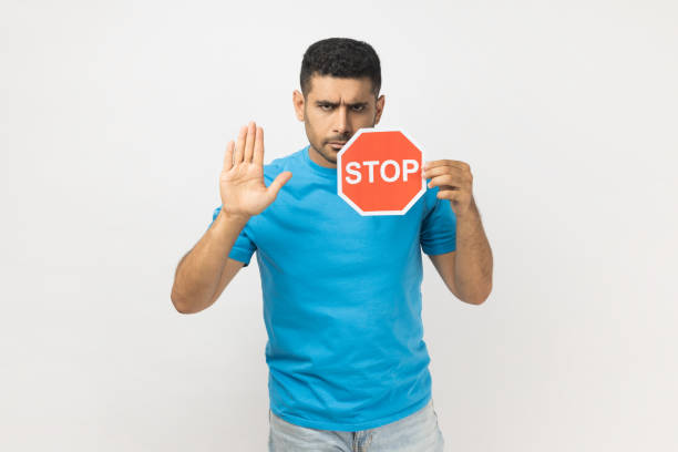 istock Serious man holding red stop sign and ban gesture with palm, negative aggressive expression. 2160938445