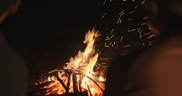 istock Evening Campfire with Two People Sitting Nearby, Firelight in Focus 2160939980