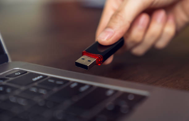 istock Hand holding usb flash drive with connecting to laptop at wooden table 2160946016