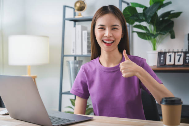 istock Young attractive female sitting at the desk and using laptop computer with shows like sign. 2160949685