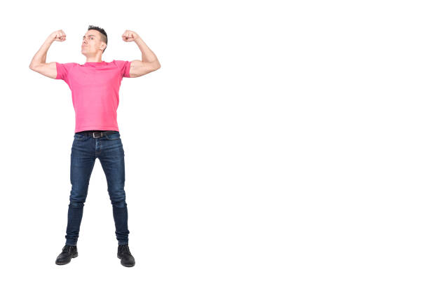 Full length of young strong male model with dark hair in casual outfit showing biceps and looking at camera with confidence against white background