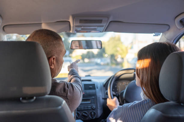 A male driving instuctor points out hazards to young female student