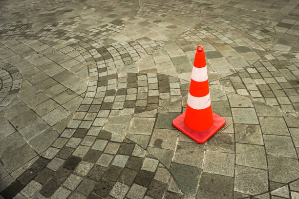 istock Orange and white colored traffic cone placed on a cobblestone road. 2160954074