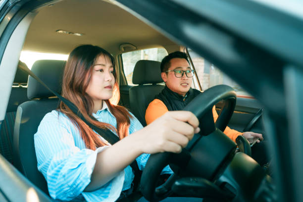 istock Instructor guiding student to drive car. 2160955102