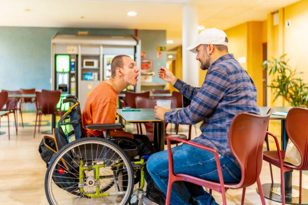 istock Man feeding a colleague with disability in a coworking cafeteria 2160956781