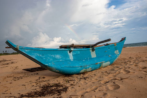 old wooden fishing boat in beach , clouds background , lonely beach